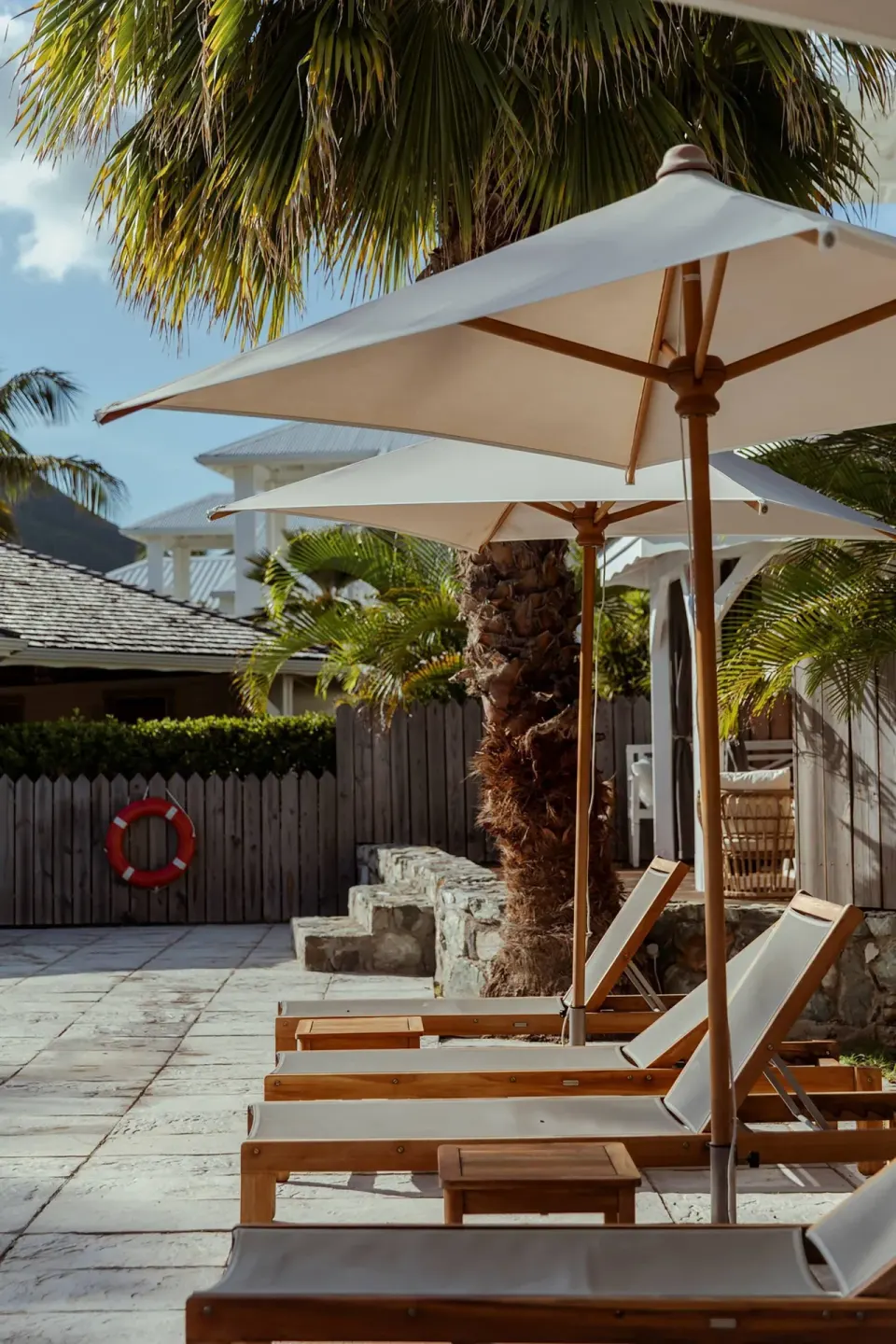 Poolside lounge chairs and white umbrellas beneath palm trees at La Playa Orient Bay.