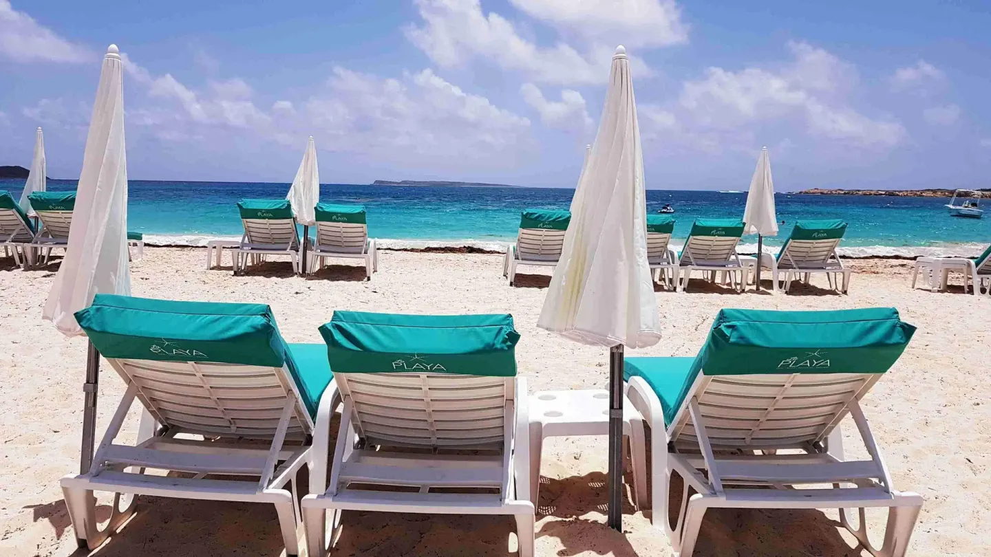 Beach loungers and white umbrellas facing the sea at La Playa Orient Bay.