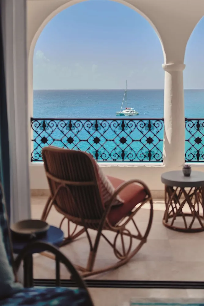 Arched balcony with a rocking chair and sailboat view at La Samanna, St Martin.