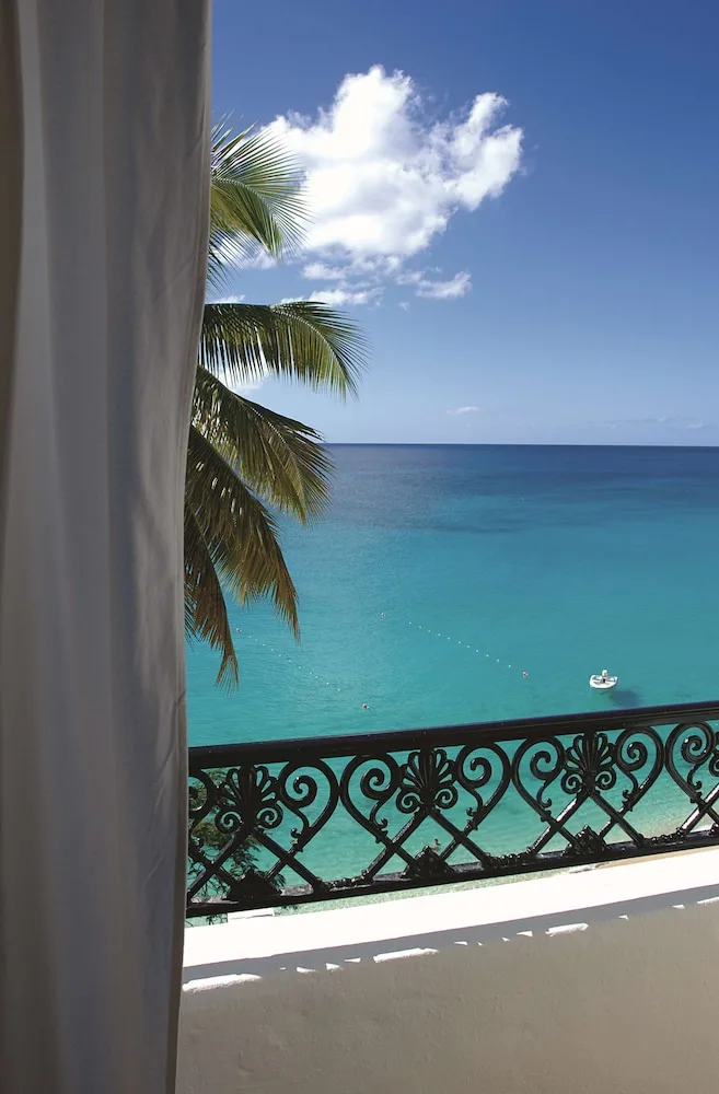 Balcony railing, palm fronds, and turquoise sea view at La Samanna, St Martin.
