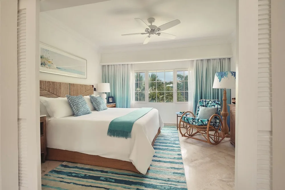 King bedroom with striped rug and tropical greenery outside at La Samanna, St Martin.