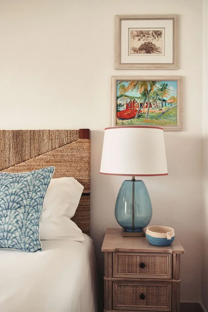 Bedside table with blue glass lamp and framed art at La Samanna, St Martin.