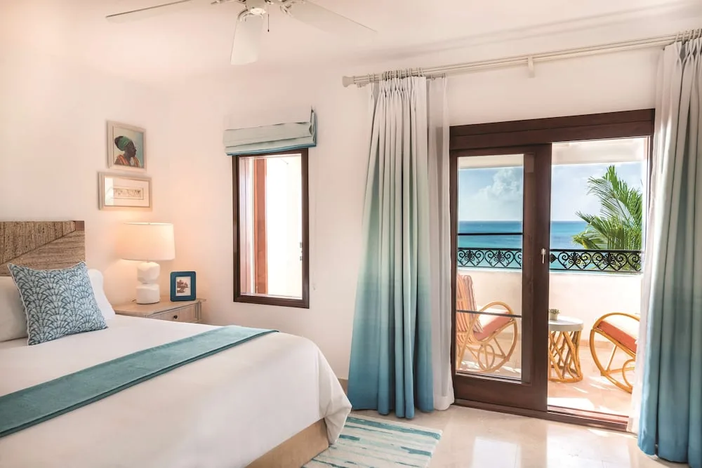 Guest room with a bed and balcony ocean view at La Samanna, St Martin.