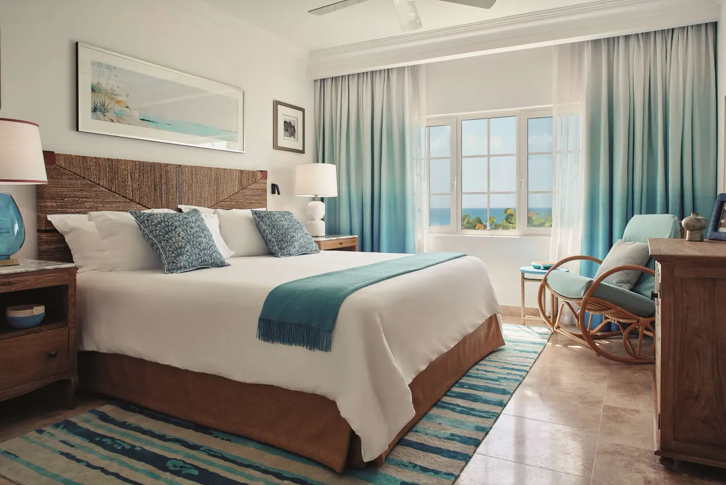 Guest room king bed with turquoise accents and ocean-facing windows at La Samanna, St Martin.