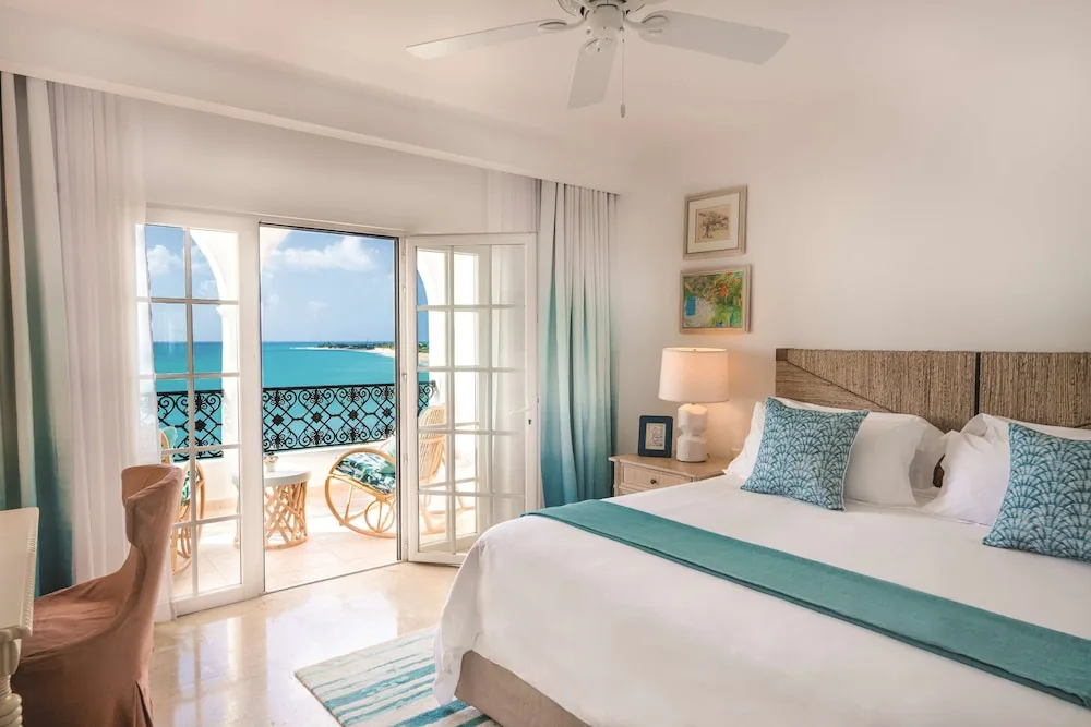 Guest room with a king bed and open doors to the sea at La Samanna, St Martin.