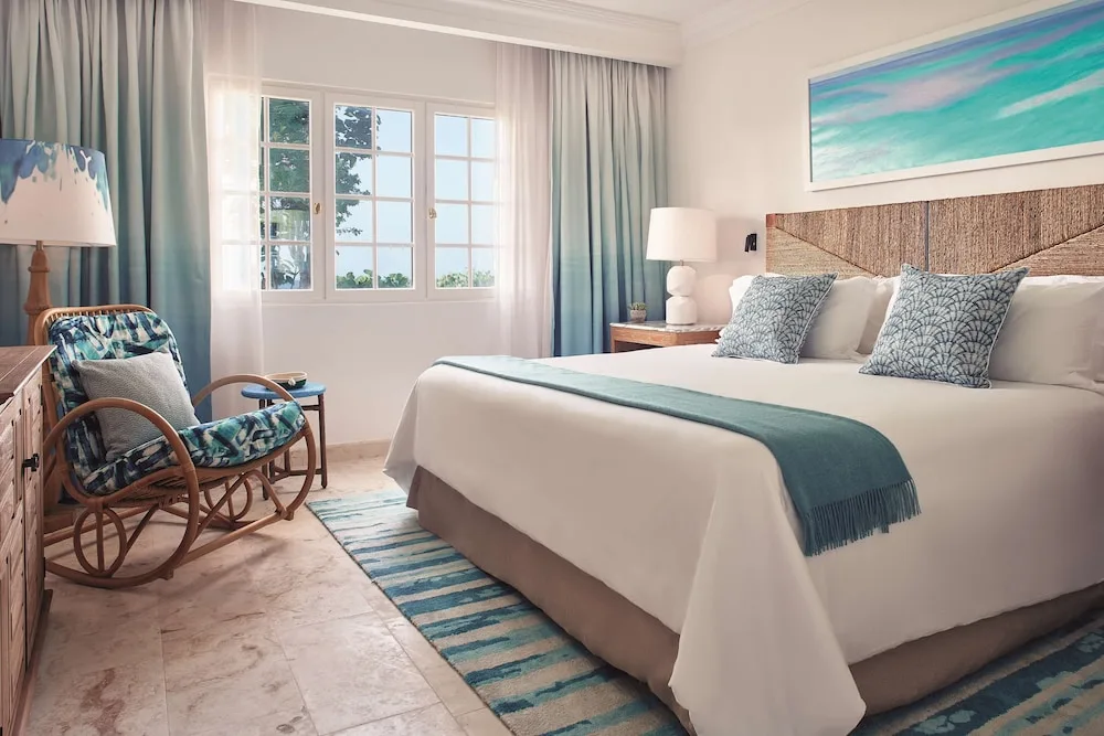 King guest room with rattan lounge chair and glimpse of the sea at La Samanna, St Martin.