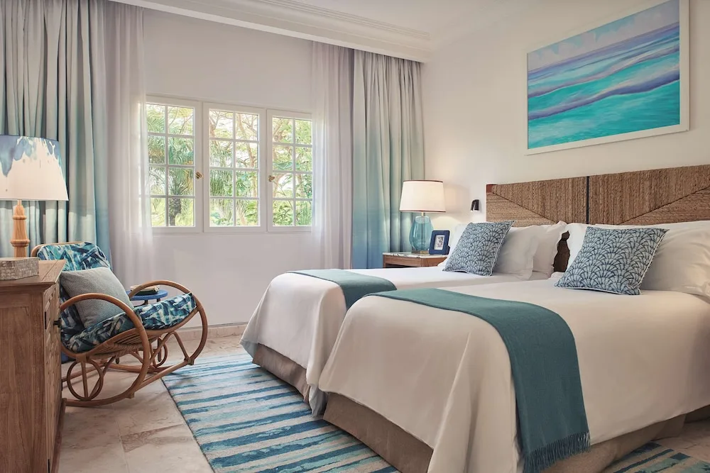 Twin-bed guest room with rattan chair and garden-facing windows at La Samanna, St Martin.