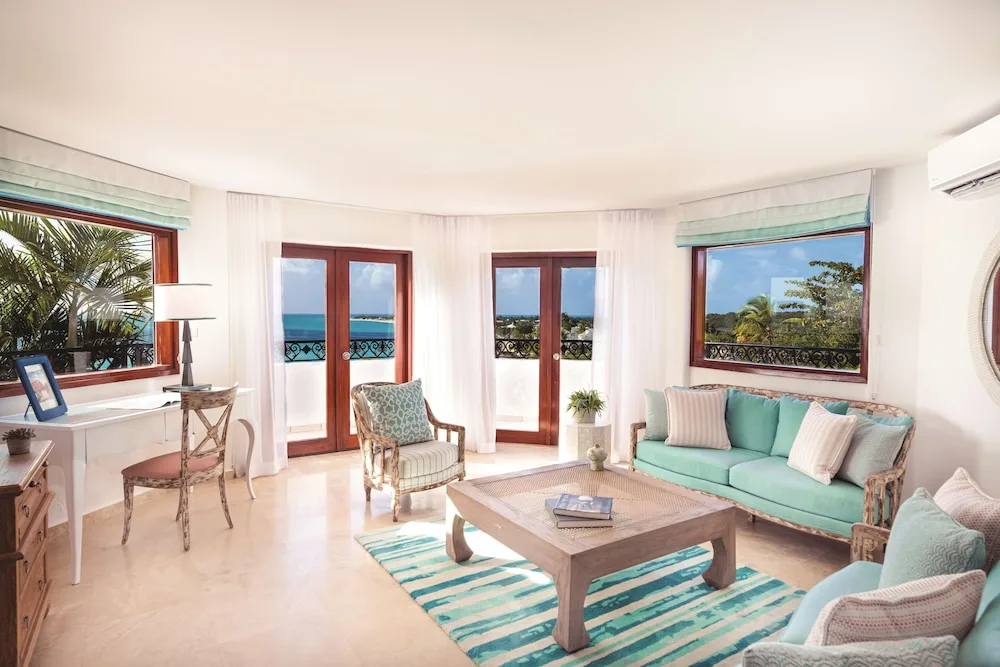 Ocean-view living room with turquoise sofa and balcony doors at La Samanna, St Martin.