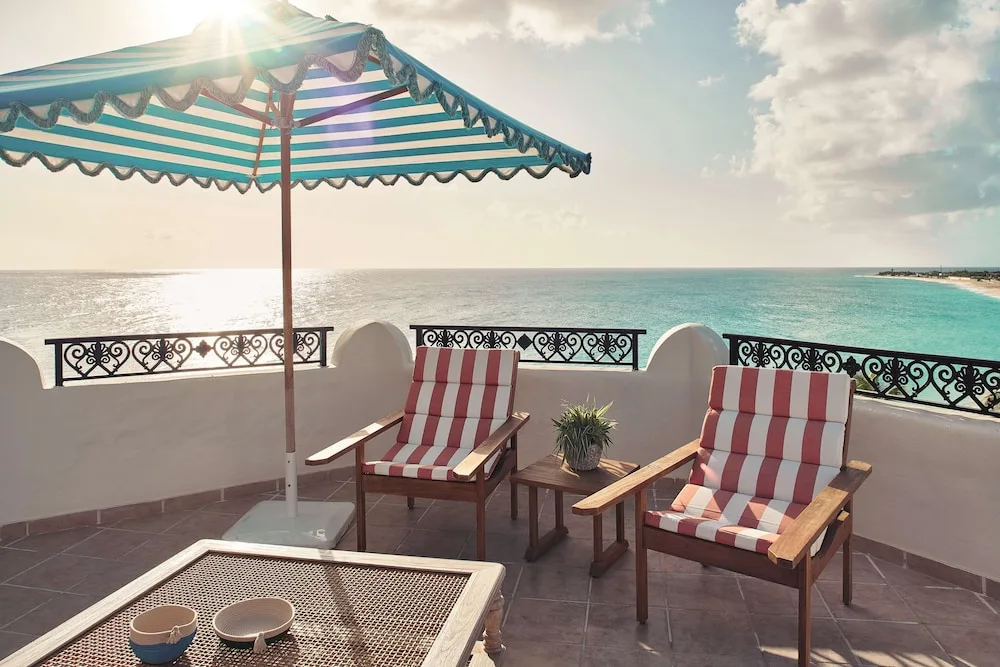 Oceanfront terrace with striped chairs and umbrella at La Samanna, St Martin.