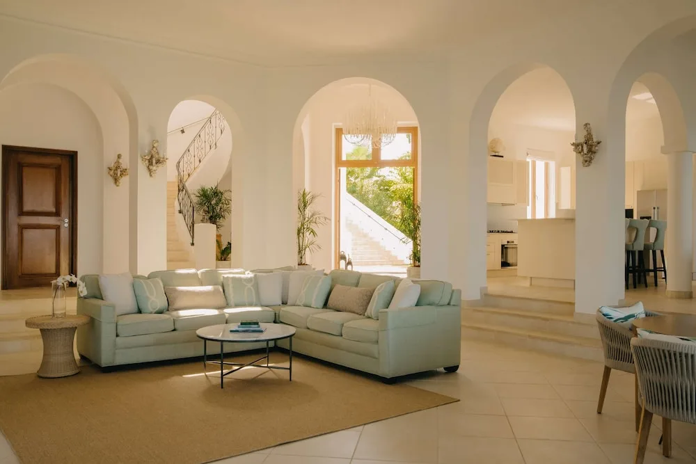 Open living room with sectional sofa, arches and kitchen beyond at La Samanna, St Martin.