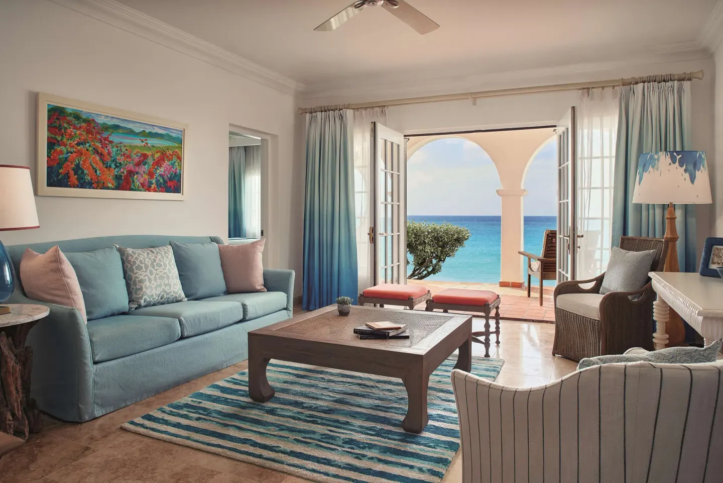 Suite living room with blue sofa and arched terrace facing the sea at La Samanna, St Martin.