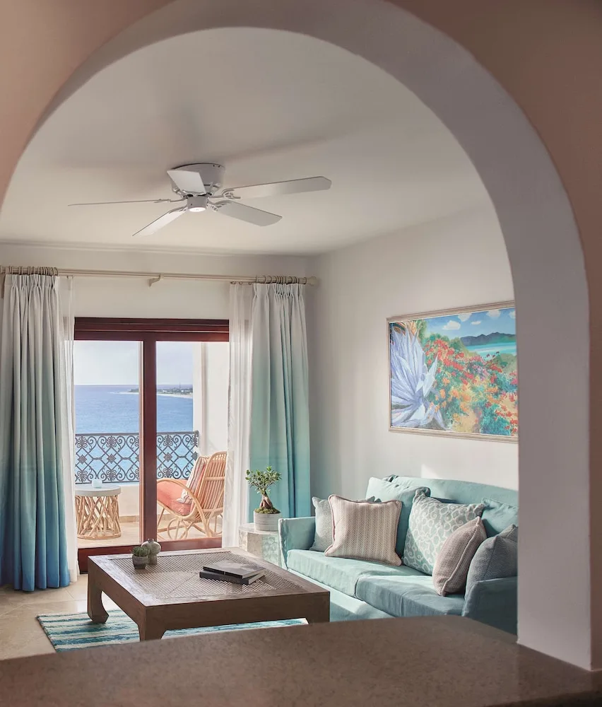 Suite sitting room seen through an arch with balcony and ocean view at La Samanna, St Martin.