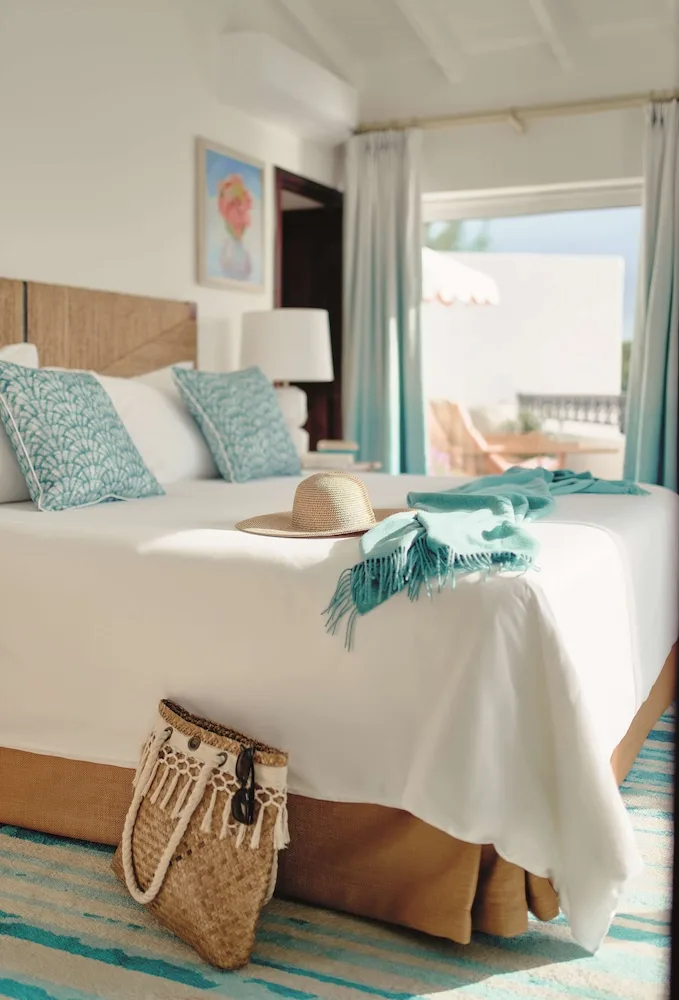 Sunlit king bed with straw hat and woven beach bag at La Samanna, St Martin.
