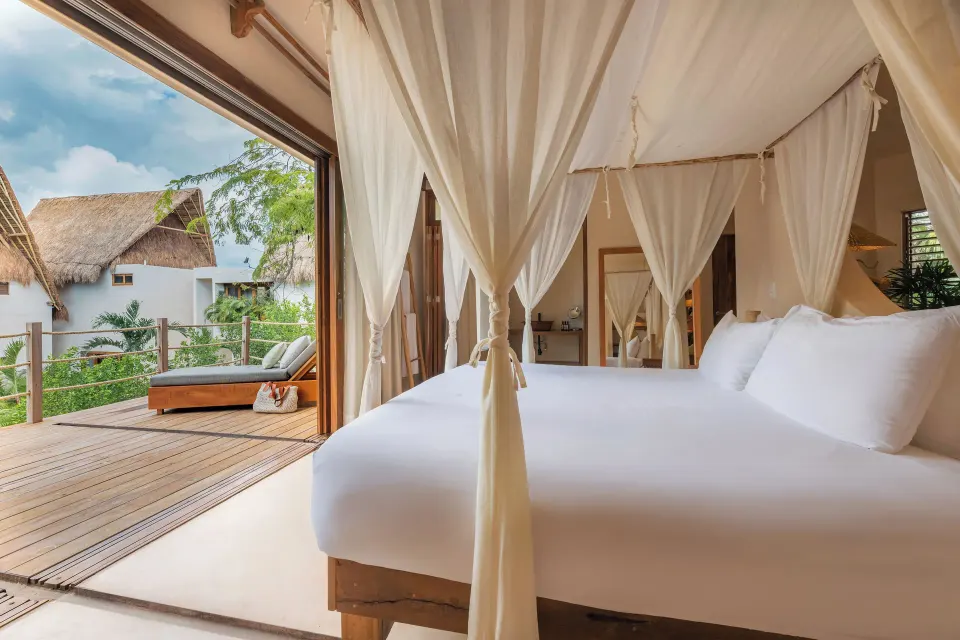 Four-poster bed beside an open deck with sunbed at La Valise Tulum