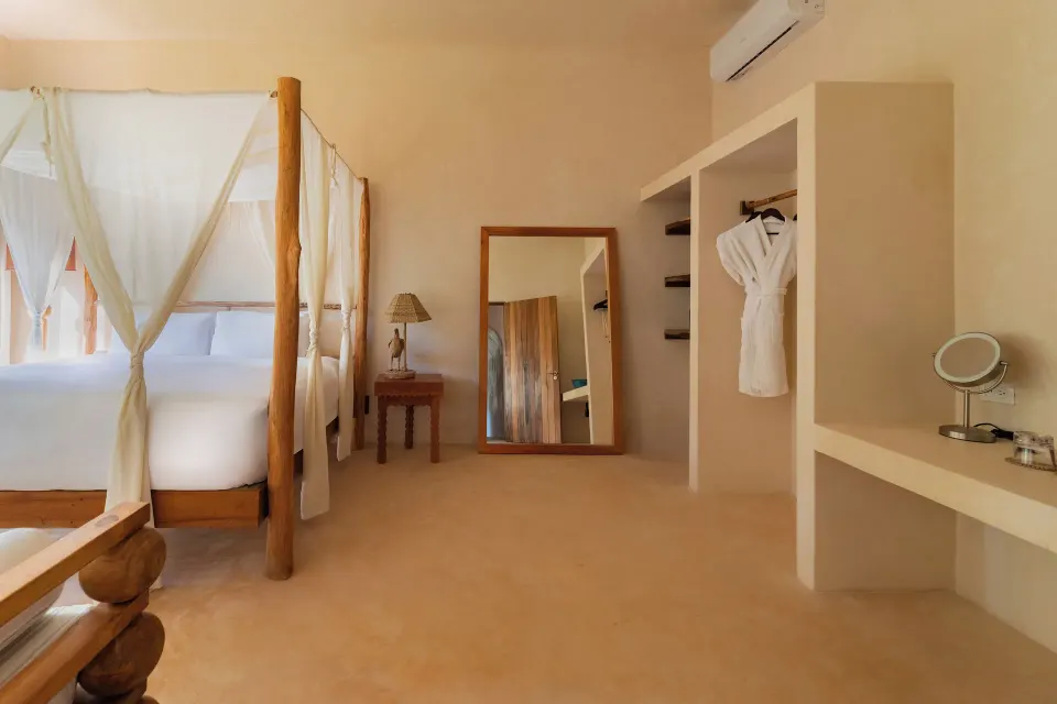 Canopy king bed and open wardrobe in a guest room at La Valise Tulum.