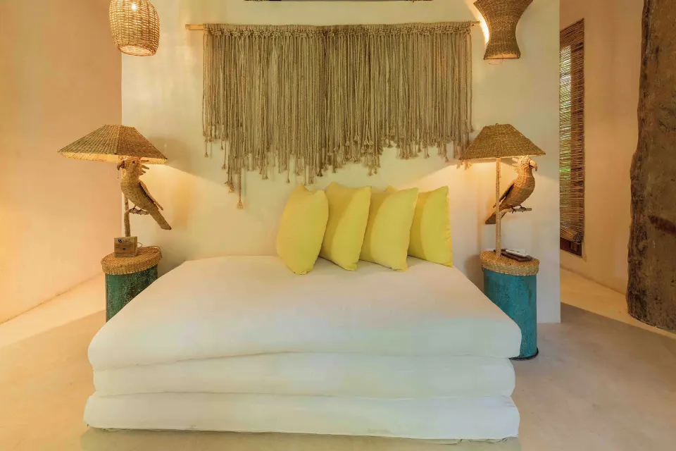 Low modern sofa with bright accent pillows and woven wall hanging at La Valise Tulum.