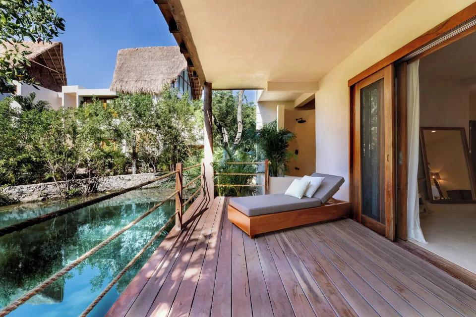 Private wooden deck with chaise lounge beside a lagoon at La Valise Tulum.