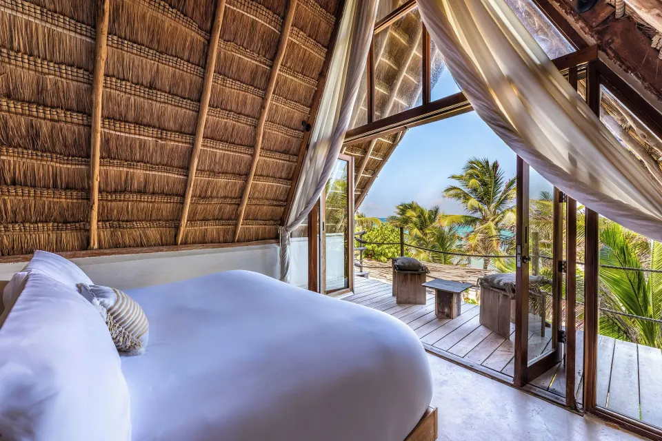 Lofted bedroom with round bed and balcony overlooking palms and ocean at La Valise Tulum.