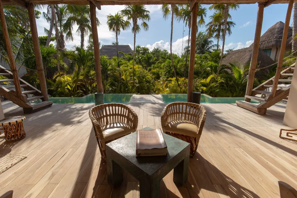 Two woven chairs facing a private plunge pool and lush palms from a wooden deck at La Valise Tulum