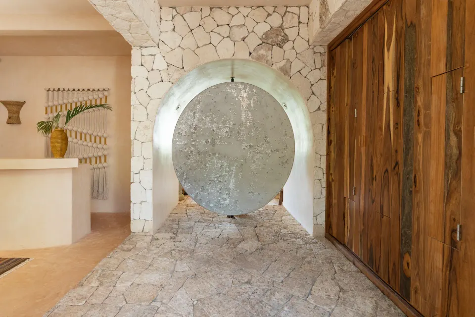 Circular metal sculpture in a stone corridor within the lobby at La Valise Tulum.