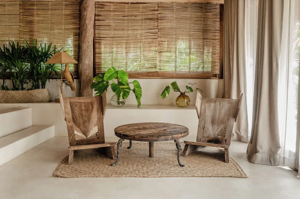 Two rustic wooden chairs and round table in a neutral seating nook at La Valise Tulum.