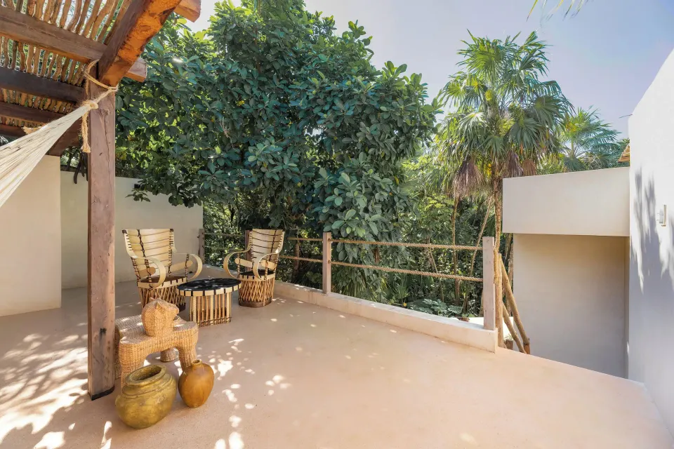 Shaded terrace with woven chairs, hammock and decorative pottery at La Valise Tulum.