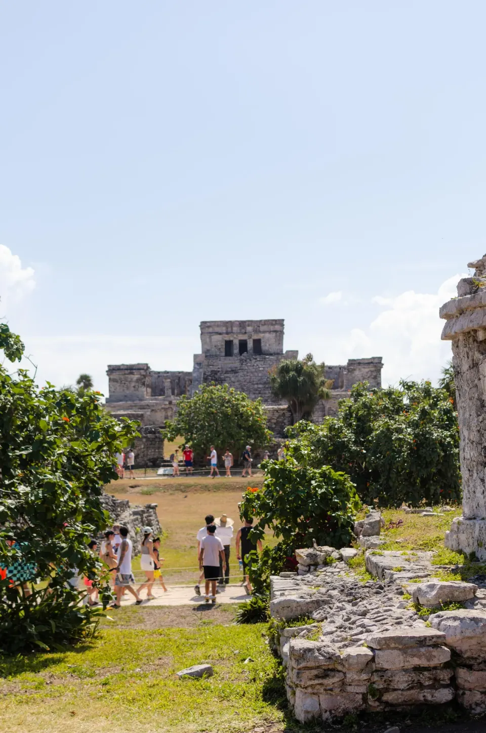 Historic stone temple and visitors framed by greenery at La Valise Tulum