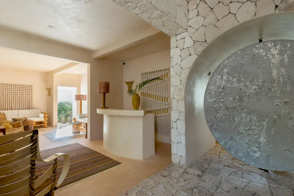 Interior view of a stone-walled lobby entrance with sculptural circular door at La Valise Tulum.