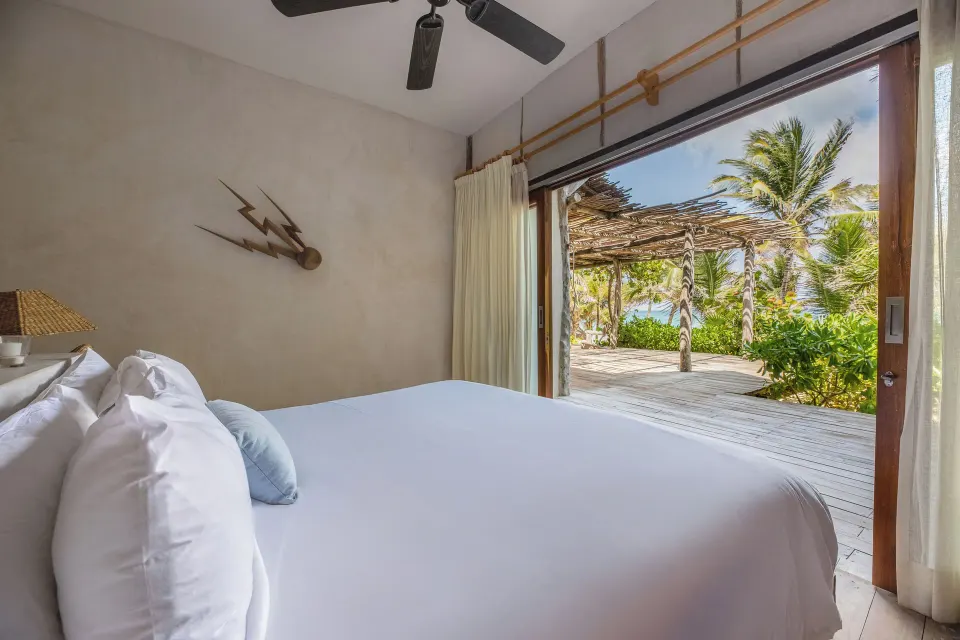 King bed in a bright room opening to a shaded outdoor terrace at La Valise Tulum