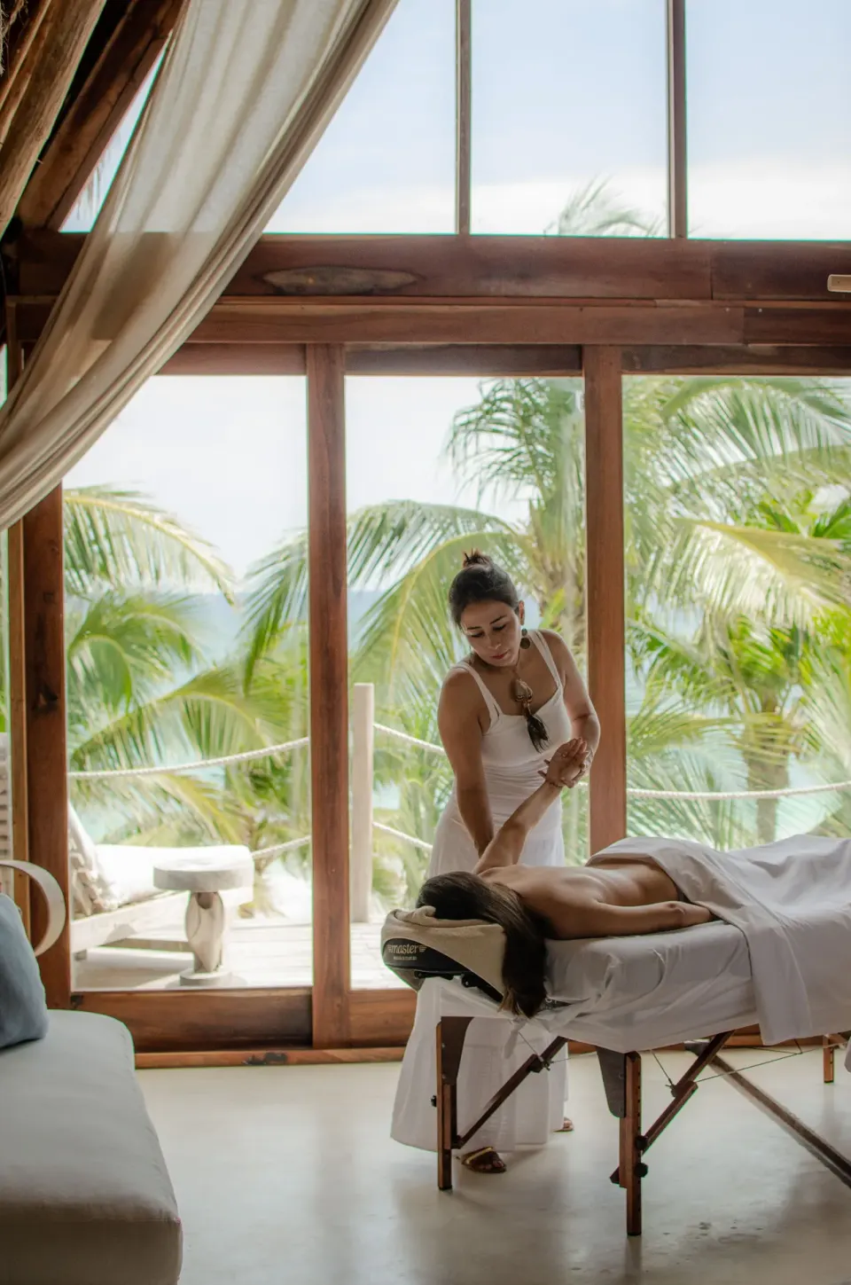 Massage treatment table by sliding doors with palm-tree views at La Valise Tulum