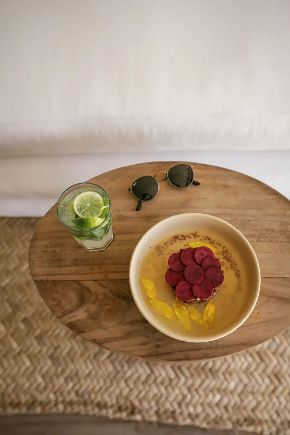 Small table with a bowl of dessert, a lime drink and sunglasses at La Valise Tulum