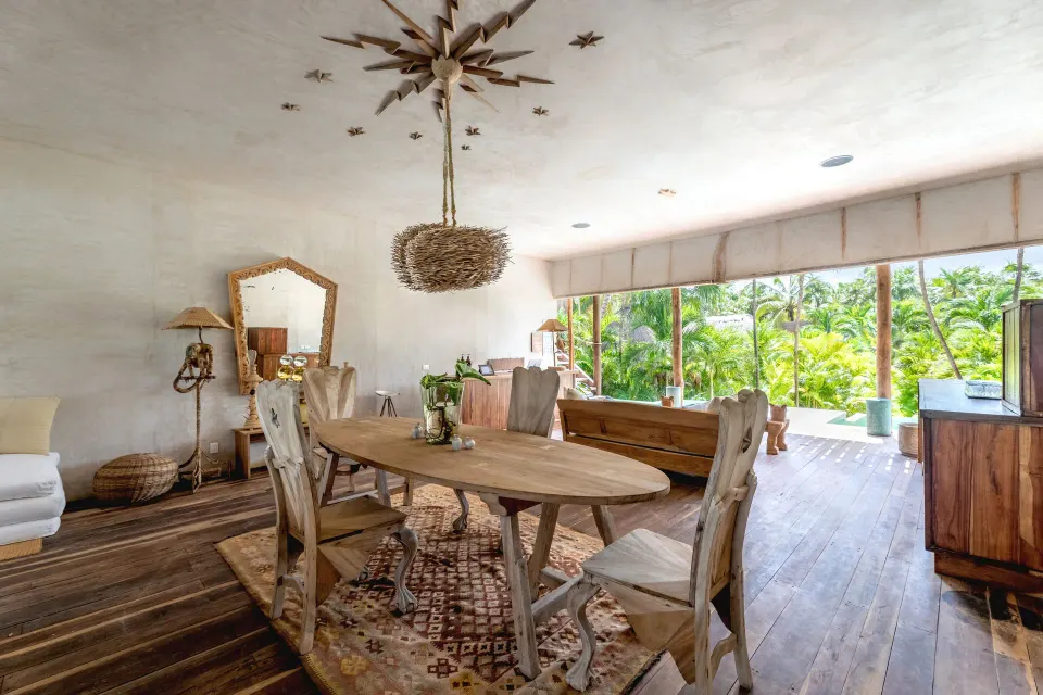 Light-filled dining area with wooden table and sliding wall at La Valise Tulum