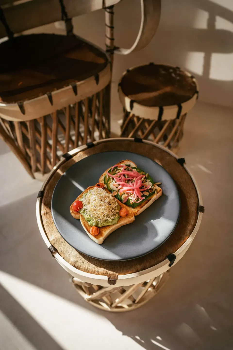 Two open-faced toasts on a blue plate on a wooden stool at La Valise Tulum