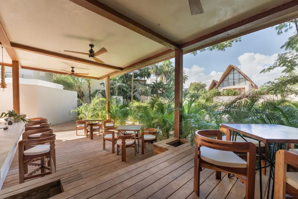 Shaded wooden dining terrace with tables and chairs at La Valise Tulum