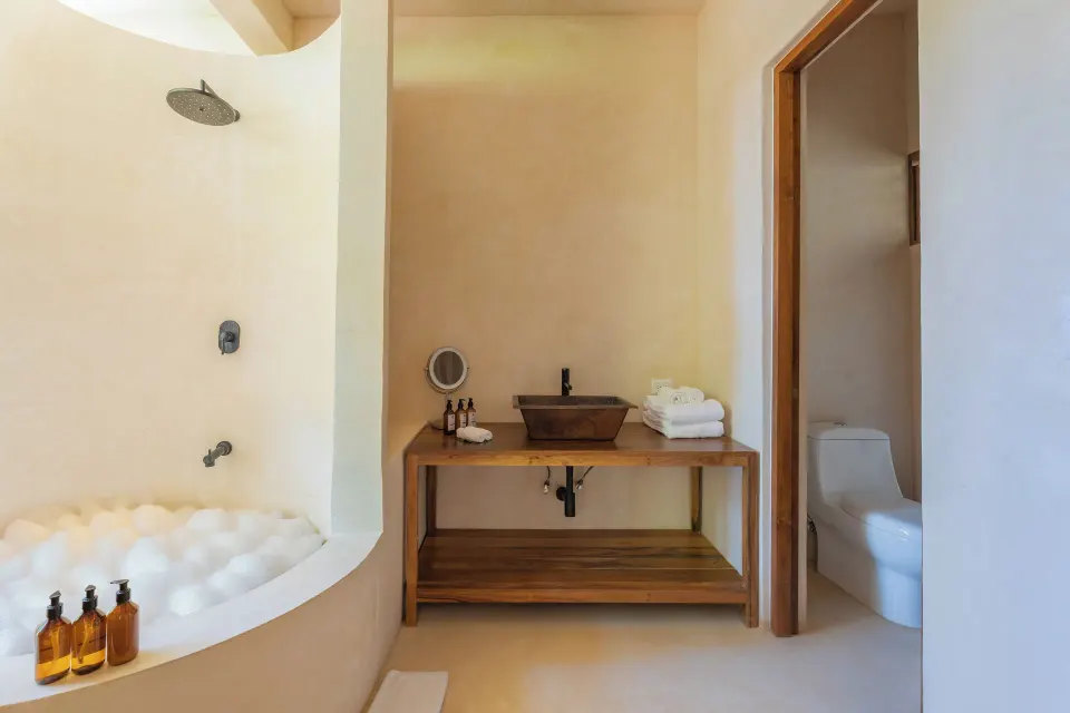Bathroom with sunken tub, wooden vanity and separate toilet in Cenote Suite Lower at La Valise Tulum