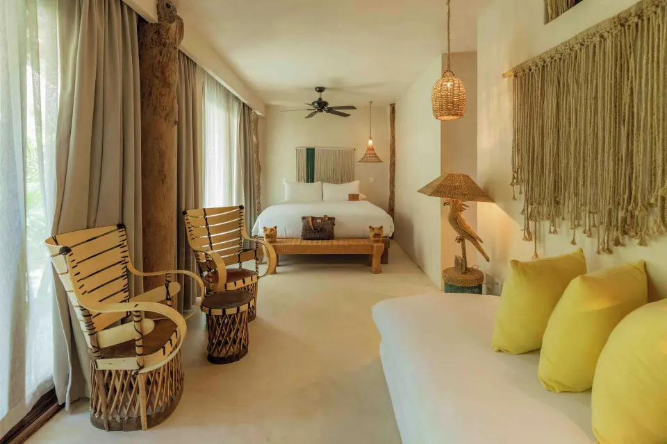 Full view of the Garden Suite Lower bedroom with king bed, chairs and sliding glass doors at La Valise Tulum