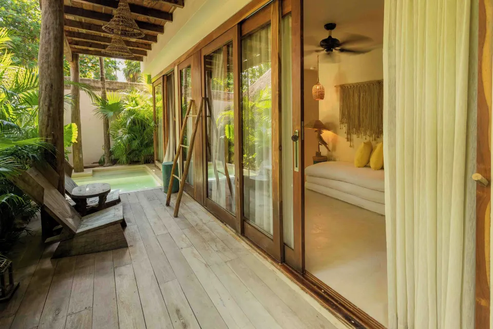 Outdoor wood deck, lounge chairs and sliding doors into Garden Suite Lower at La Valise Tulum