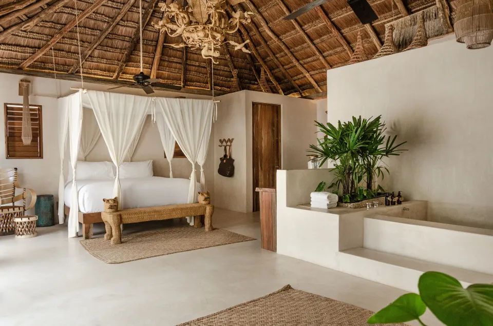 Canopy king bed and open-plan bathroom in the Garden Suite Upper at La Valise Tulum.