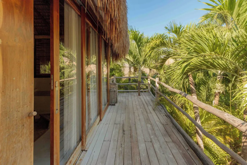 Private wooden balcony overlooking palm foliage from the Garden Suite Upper at La Valise Tulum.