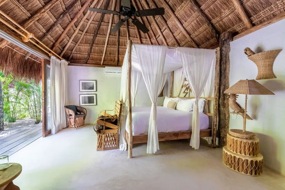 Four-poster king bed with white drapes inside a Garden View Room at La Valise Tulum.