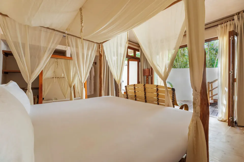 Close-up of the four-poster king bed with flowing canopy drapes in a Jungle View Room at La Valise Tulum.