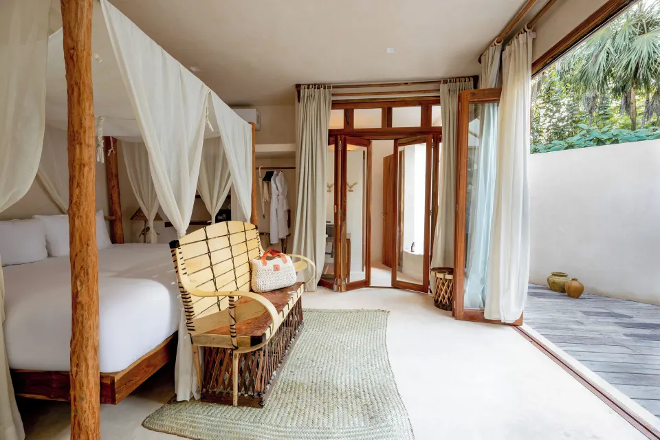 Four-poster king bed and open glass doors to a private terrace in a Jungle View Room at La Valise Tulum.