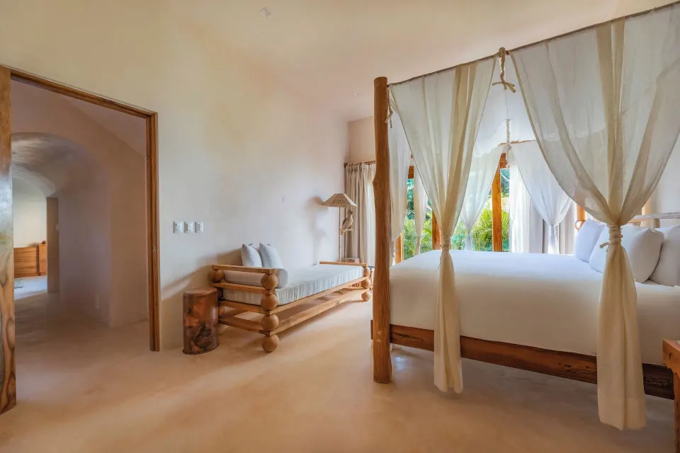 Four-poster king bed and lounge area in a Junior Room at La Valise Tulum.