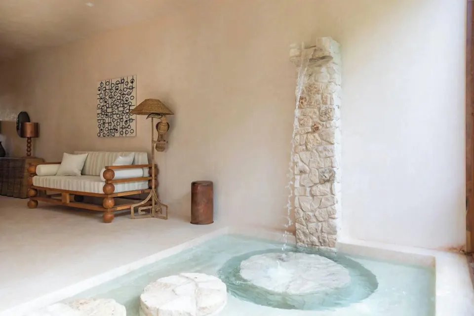 Indoor plunge pool with stone water feature and sofa in Signature Suite at La Valise Tulum