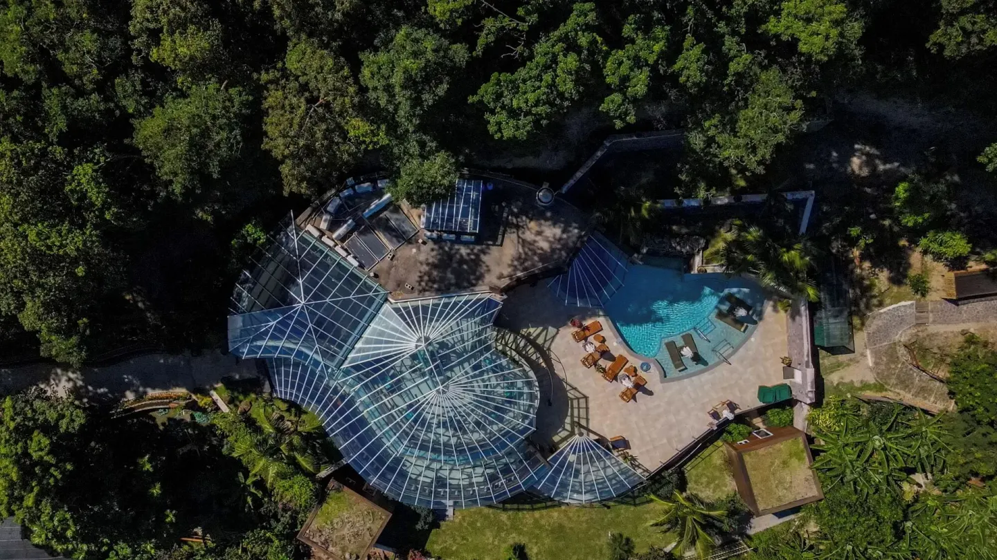 An aerial view shows Ladera Resort buildings, pool terrace, and surrounding forest.