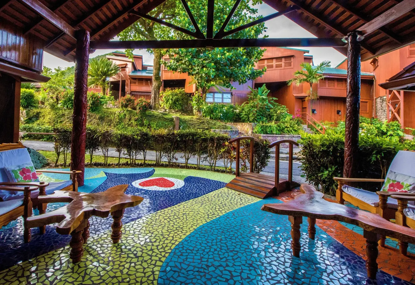 Colorful mosaic terrace with wooden chairs and garden buildings at Ladera Resort.