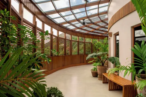 A curved indoor walkway with plants, wood shutters, and a glass roof at Ladera Resort.