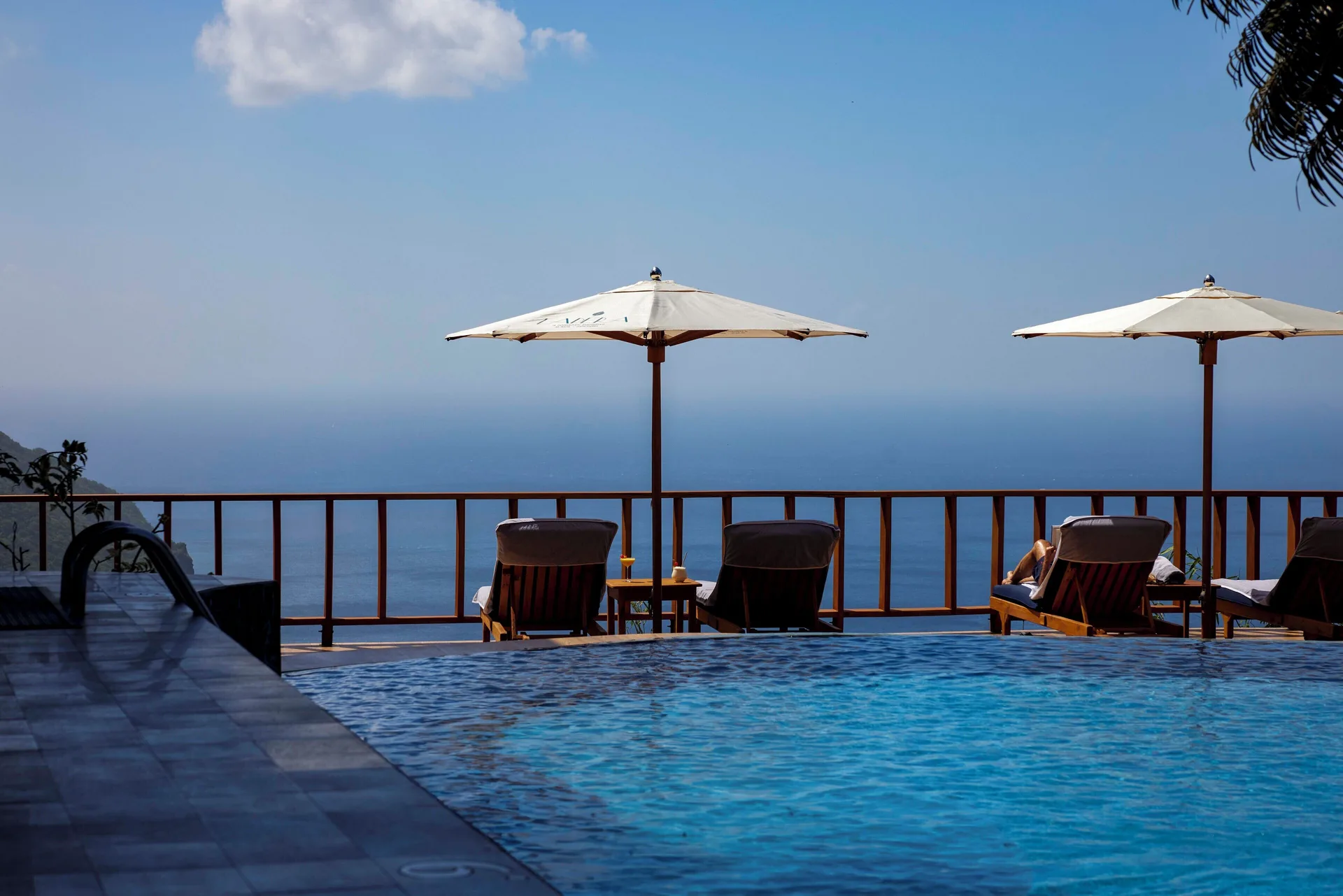 Infinity pool with lounge chairs, umbrellas, and ocean view at Ladera Resort.
