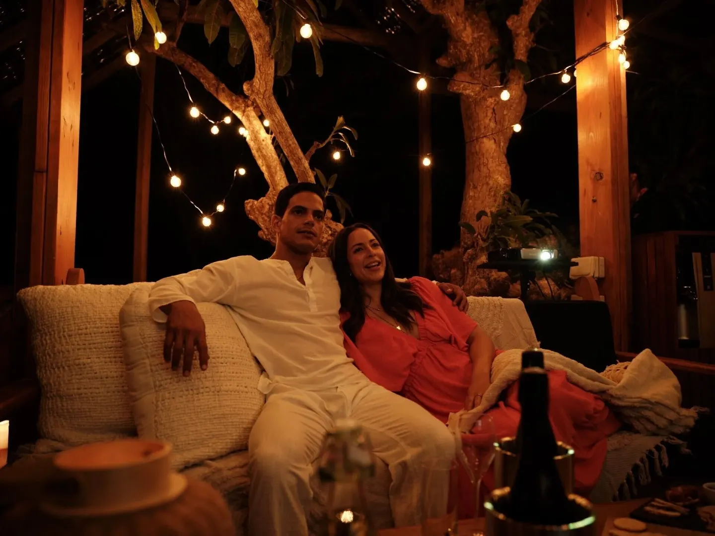 Couple seated on an outdoor sofa under string lights at Ladera Resort.