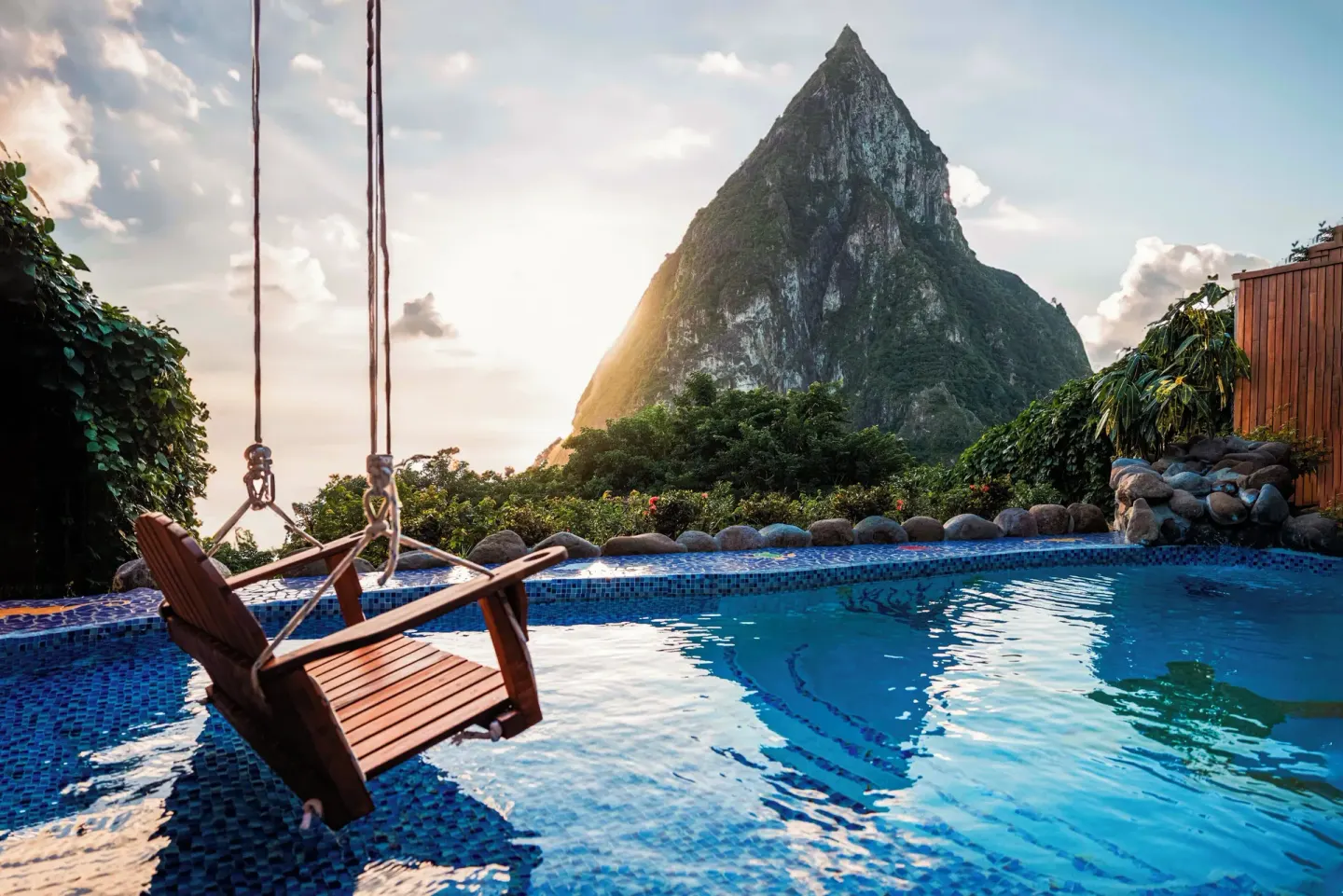Swimming pool with a hanging wooden chair and Piton view at Ladera Resort.